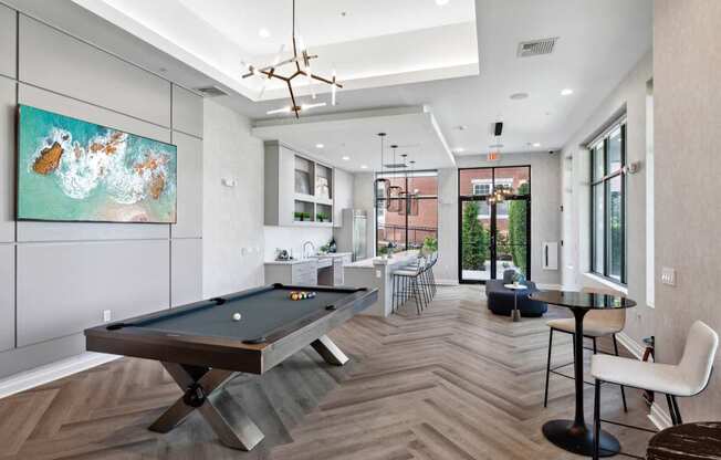 A pool table is in the middle of a room with a chair and a table.