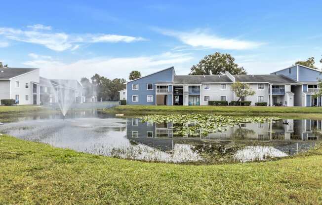 a pond with a fountain in front of apartment buildings