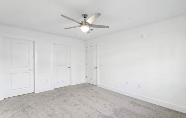 A room with a ceiling fan and carpeted floor.