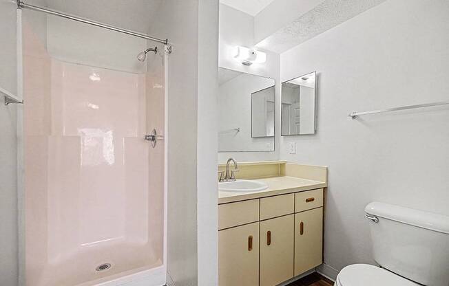 A white bathroom with a toilet, sink, and shower.