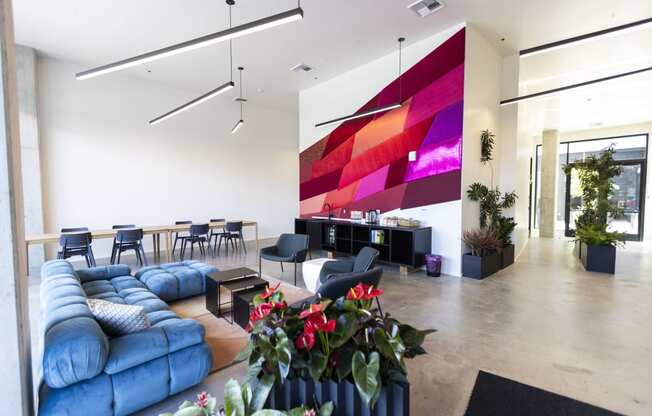 a large living room with blue furniture and a large colorful wall in the middle at Analog PDX Apartments, Portland, OR 97227