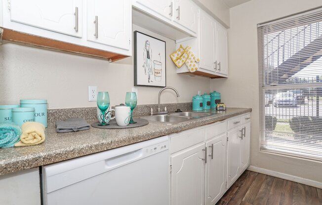A kitchen with white cabinets and a granite countertop at The Drake in Bossier City, LA