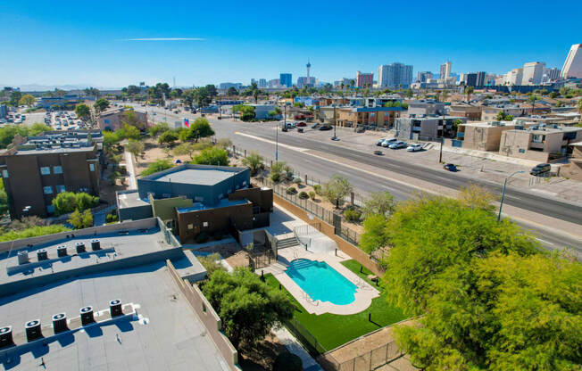 an aerial view of a parking lot with a pool and a city in the background