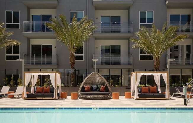 A poolside lounge area with two couches and a table with a wicker umbrella.