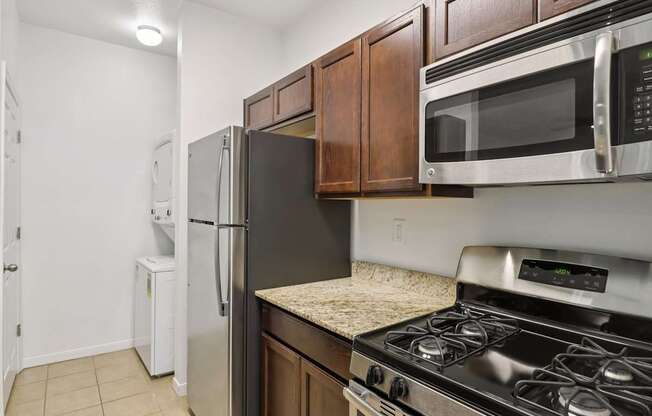 A kitchen with a black refrigerator, stove, and microwave.