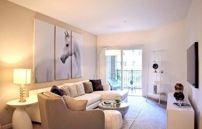 A living room with a white couch and a painting of a horse on the wall.