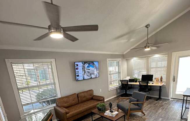 A living room with a couch, a television, and a fan.