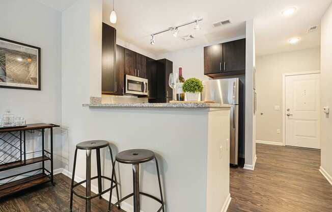 a kitchen with a bar with two stools and a refrigerator