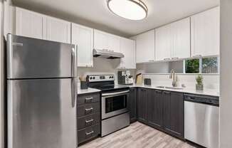 A modern kitchen with a stainless steel refrigerator and wooden flooring.