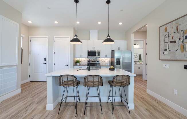 A kitchen with a white island and bar stools.