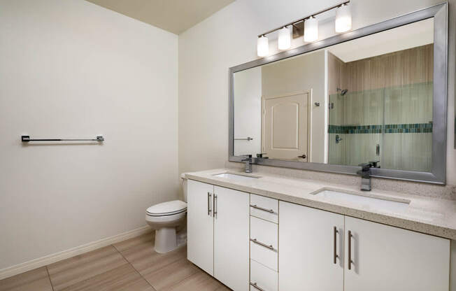 A bathroom with a toilet, sink, and mirror.