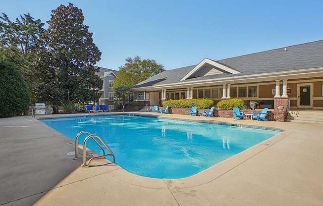 A swimming pool with a diving board and lounge chairs.