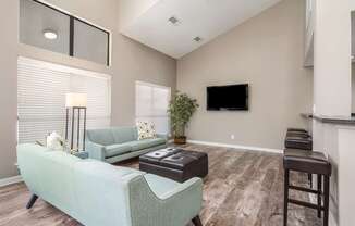 Clubhouse with a green couch and a flat screen TV mounted on the wall at Poplar Place Apartments