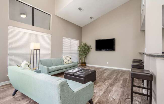 Clubhouse with a green couch and a flat screen TV mounted on the wall at Poplar Place Apartments