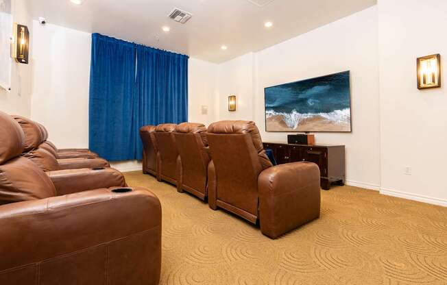 A room with brown leather chairs and a painting of a beach scene on the wall.