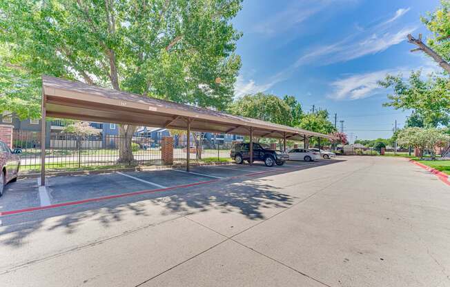 A parking lot with a covered area and a fence.