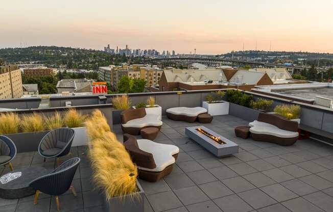 a roof deck with couches and a fire pit with a view of the city