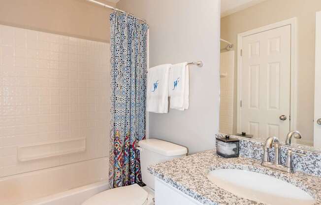 A white bathroom with a toilet, sink, and shower.