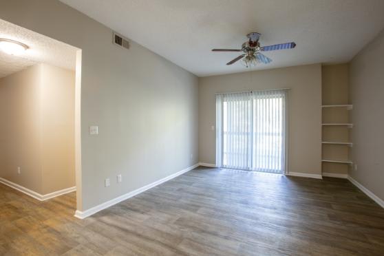 A room with a ceiling fan and wooden flooring.