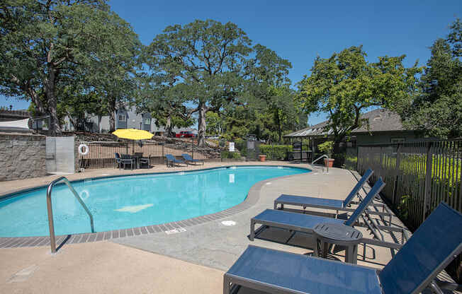 A pool surrounded by trees and chairs at Rocklin Gold Apartments, California, 95677