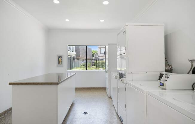 a kitchen with white cabinetry and a large window