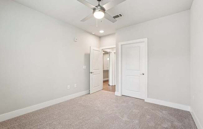 A spacious bedroom with a ceiling fan and carpeted floor