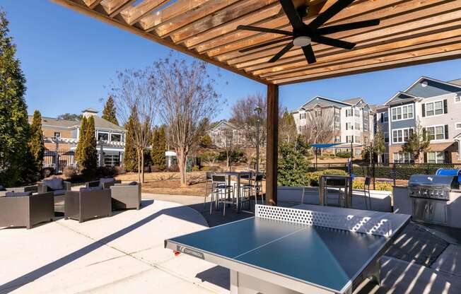 the outdoor patio has a ping pong table and a grill