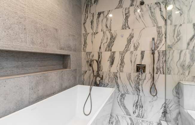 a marble bathroom with a tub and shower and a sink
