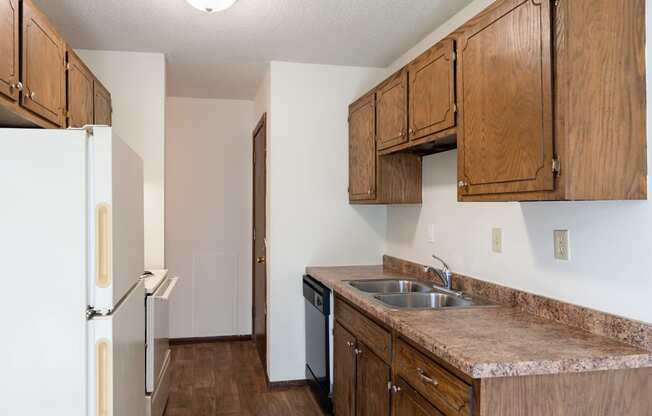 a kitchen with wooden cabinets and a sink and a refrigerator. Eagan, MN Glen Pond Apartments
