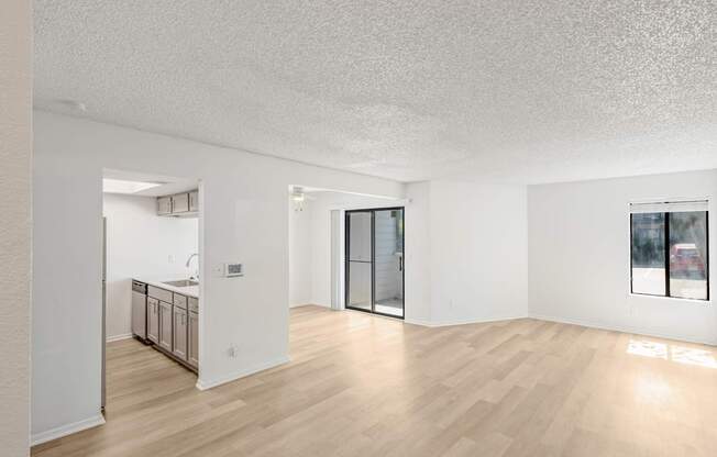 A sparsely furnished room with a kitchen area in the background.