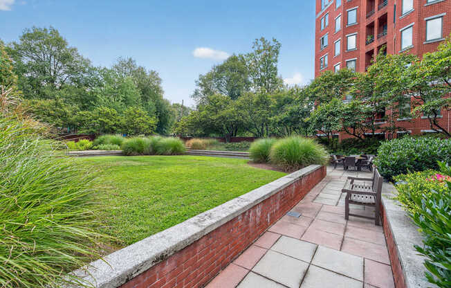 A brick wall separates a patio from a grassy area.