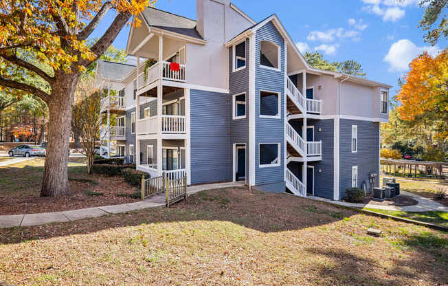 A large apartment complex with a tree in front of it.
