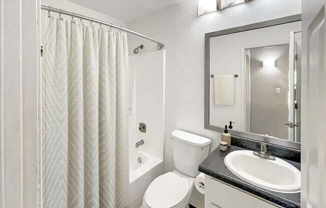 A white bathroom with a toilet, sink, and shower.