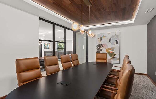 A conference room with a long table and brown leather chairs.