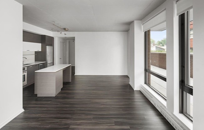 an empty living room and kitchen with wood floors