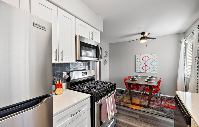 spacious kitchen with stainless steel appliances and white cabinets and a dining room table with chairs