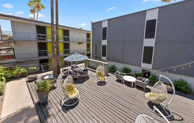 a patio with chairs and an umbrella in front of a building