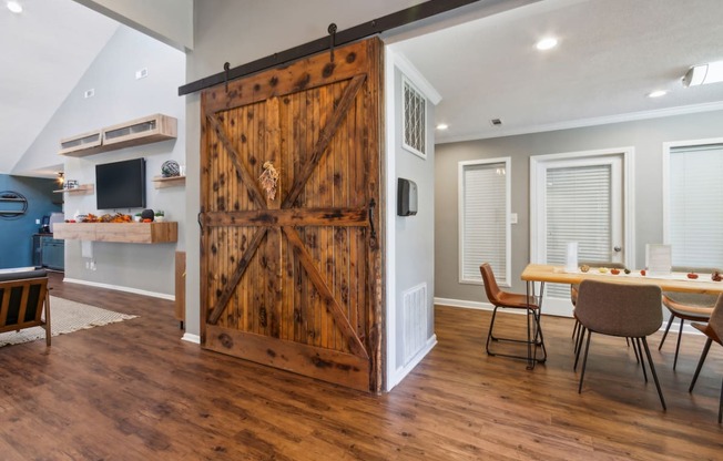 a barn door in the center of a living room with a table and chairs