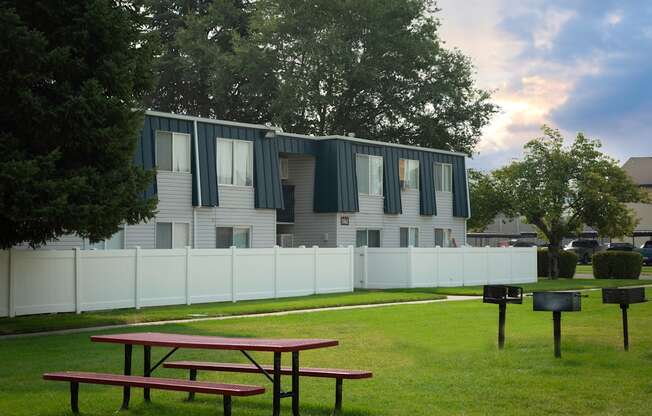 an apartment building with a white fence and two picnic tables