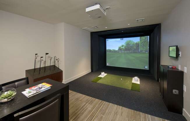 a living room with a golf simulator and a view of a putting green