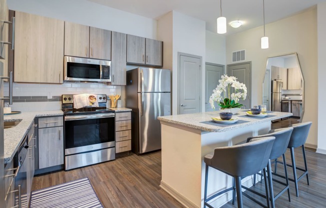 an open kitchen and dining area with stainless steel appliances and a table with chairs