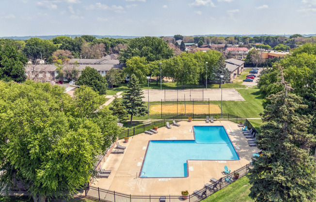 an aerial view of a swimming pool in a park with trees