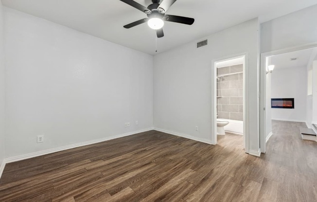 an empty living room with a ceiling fan and a bathroom