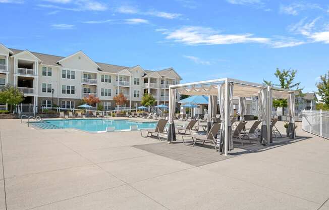 a swimming pool with chaise lounge chairs in front of an apartment building