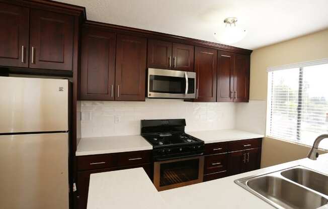 a kitchen with dark cabinets and a sink and a refrigerator