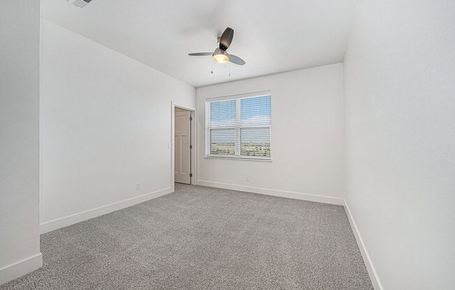 bedroom with a large window and ceiling fan at Trade Winds Apartment Homes, Elkhorn, NE