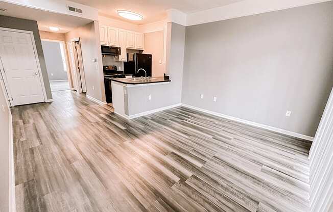 a renovated living room with wood flooring and a kitchen