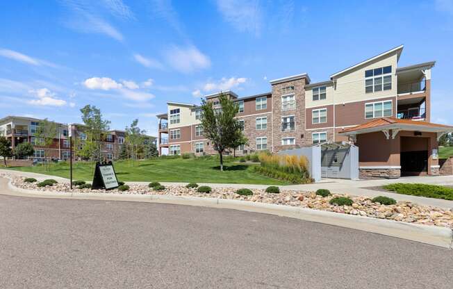 an exterior view of an apartment building with a gravel driveway and landscaping at Ridge at Thornton Station Apartments, Thornton, Colorado