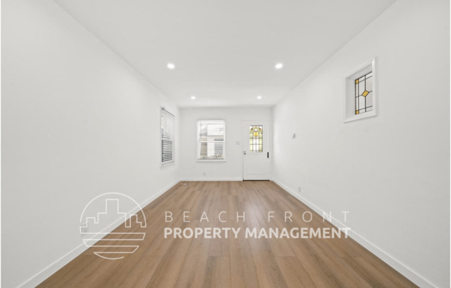 a white room with a hardwood floor and a white door