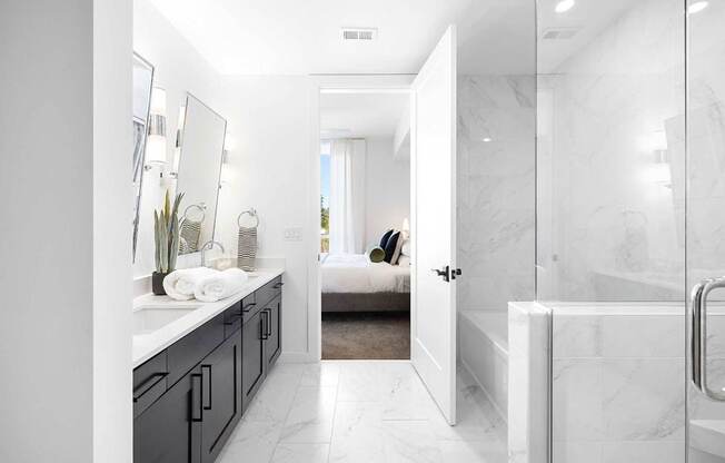 A bathroom with a white marble floor and walls, a white sink, and a glass shower door.